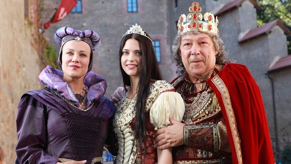 Zwei Schauspielerinnen in mittelalterlichen Kleidern und ein Schauspieler mit Krone im Königskostüm.