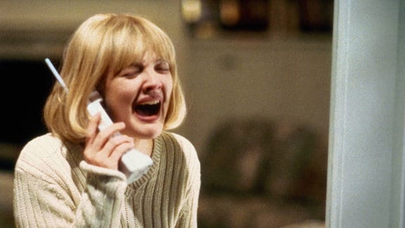 Drew Barrymore im Film "Scream": sie hält ein Telefon ans Ohr und schreit