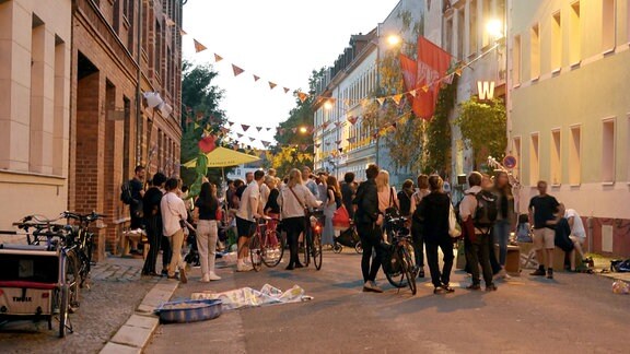 Menschen in einer mit Wimpeln geschmückten Straße.