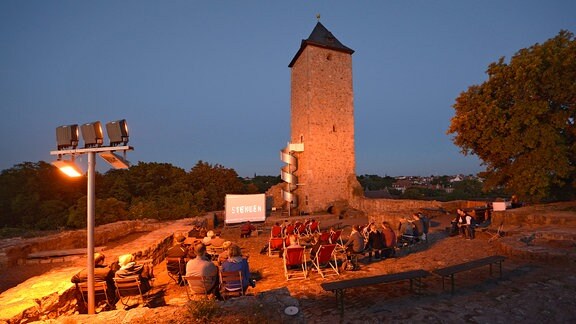 Menschen im Sommerkino, dahinter der Turm der Burg Giebichenstein