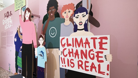Eine Art Aufsteller, der einige Demonstrierende zeigt. eine Frau hält ein Schild mit "Climate Change is real".
