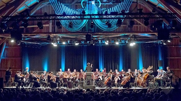Ein Orchester auf der Bühne, die blau angestrahlt wird.