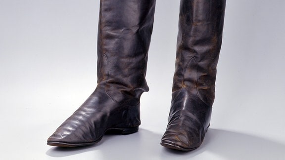 Historische Stiefel aus Leder mit hohem Schaft vor einem neutralen Hintergrund