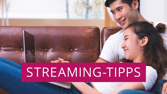 Ein Paar sitzt mit einem Laptop auf einer Ledercouch, darüber steht "Streaming Tipps".