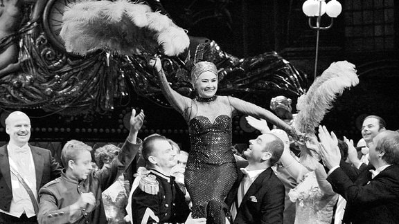 Schauspielerin Hildegard Wiczonke wird von Männern bei einer Gala getragen.