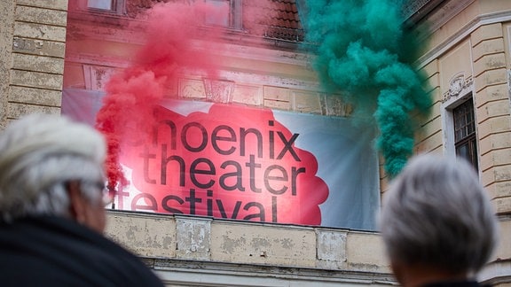 Roter und grüner Rauch steigt neben dem Schriftzug "Phoenix Theater Festival" empor.