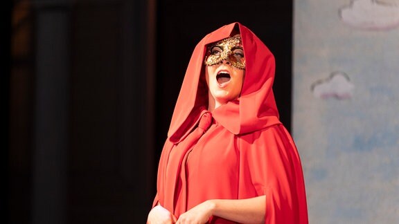 Szenenbild aus de Stück "Redoute in Reuss" am Theater Altenburg Gera, eien Frau in rotem Umhang und goldener Maske ist zu sehen