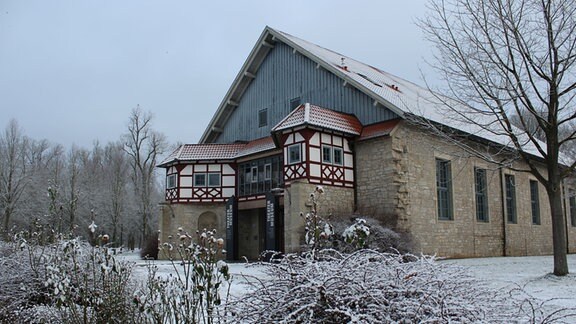 Ein großes, altes Gebäude mit schlichten grauen Mauern in winterlicher Landschaft mit Raureif