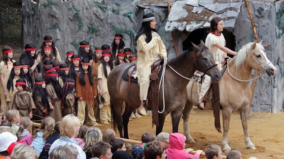 Darstellende bei den Karl-May-Spielen in Bischofswerda. Kinder, die Apachen verkörpern und zwei Schauspieler auf ihren Pferden.