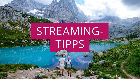 Ein Paar steht vor dem Sorapis-See in den italienischen Dolomiten, daneben der Schriftzug Streaming-Tipps.