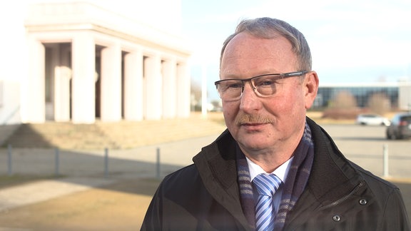 Mann mit Brille (Oberbürgermeister von Bitterfeld-Wolfen Armin Schenk) steht vor dem Kulturpalast Bitterfeld. 