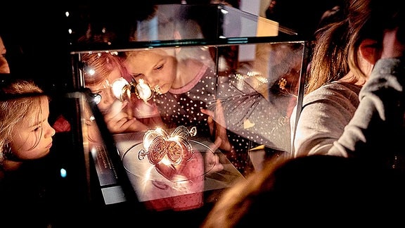 Mehrere Kinder schauen sich ein Ausstellungsobjekt in einer Glasvitrine an