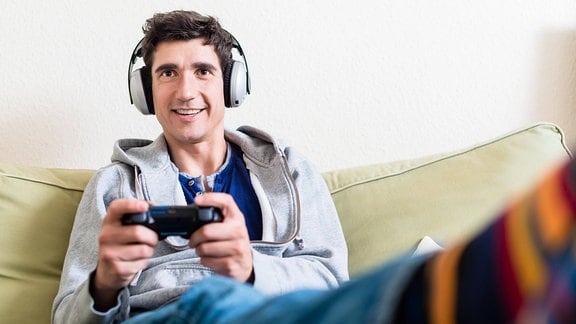 Glücklicher junger Mann spielt Videospiel auf einer Konsole