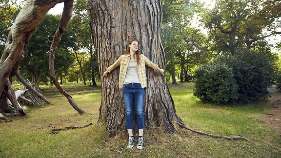 Lachende Frau an einem Baum