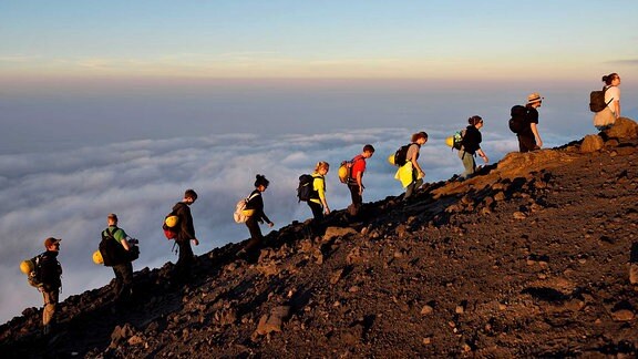 Menschen laufen auf einem Vulkan.
