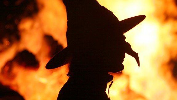 Der Kopf einer Hexe vor einem Feuer.