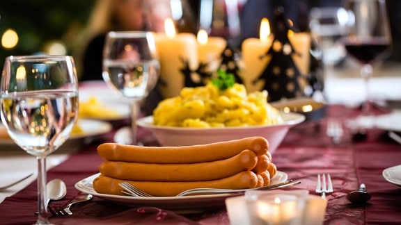 Ein festlich gedeckter Tisch mit Wiener Würstchen und Kartoffelsalat