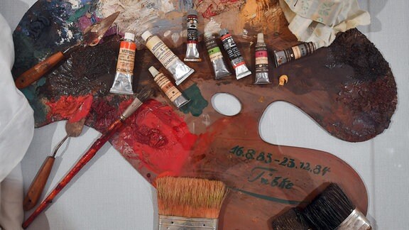 Bunte Palette eines Malers mit Farbflecken, offenen Tuben und Pinseln