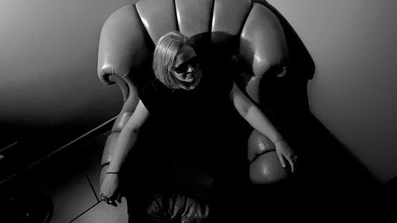 Ein schwarz-weiß Bild zeigt eine Frau in einem Ledersessel sitzend.