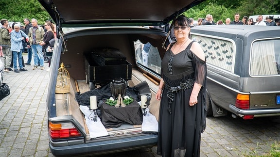 Eine Frau vor einer geöffneten Kofferraumklappe eines Leichenwagens am Südfriedhof