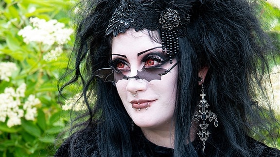 Ein Goth mit schwarzer Perücke und weißgeschminktem Gesicht.