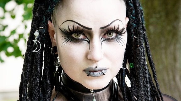 Eine Teilnehmerin des Wave-Gotik-Treffens 2024 mit schwarzem Haar und weiß geschminktem Gesicht.
