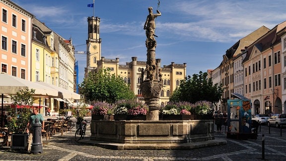 In Zittau ist der Brunnen auf dem Rathaus mit Blumenkübeln geschmückt.