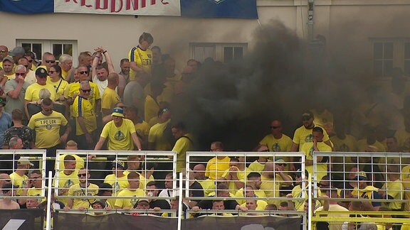 Schwarzer Rauch in der Fankurve während eines Fußballspiels