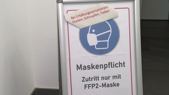 "Maskenpflicht - Zutritt nur mit FFP2-Maske" steht auf einem Aufsteller.