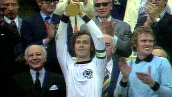 Franz Beckenbauer hebt bei der Siegerehrung der Fußball-Weltmeisterschaft 1974 den Pokal in die Höhe.