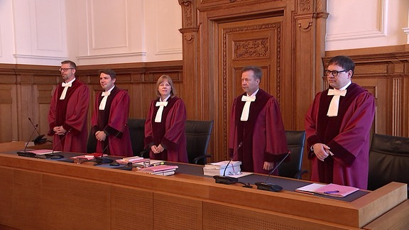 RichterInnen stehen in einem Gerichtssaal