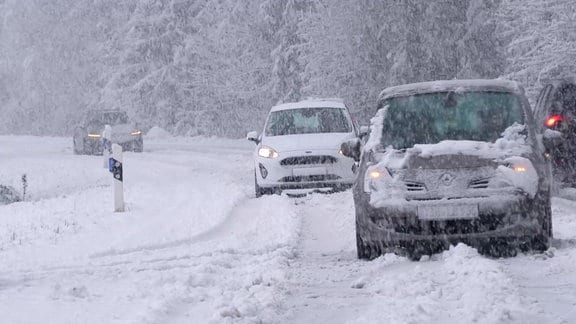 Autos fahren auf einer stark verschneiten Straße.