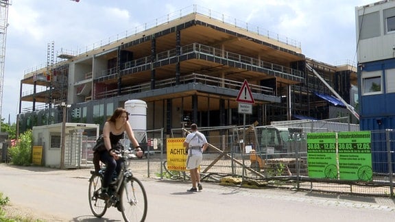 Eine Radfahrerin passiert eine Baustelle der RBLGeschäftsstelle in Leipzig