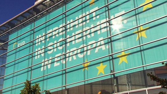 Hinter einer gläsernen Gebäudefassade ist zu lesen. "In Freiheit. In Sicherheit. In Europa."
