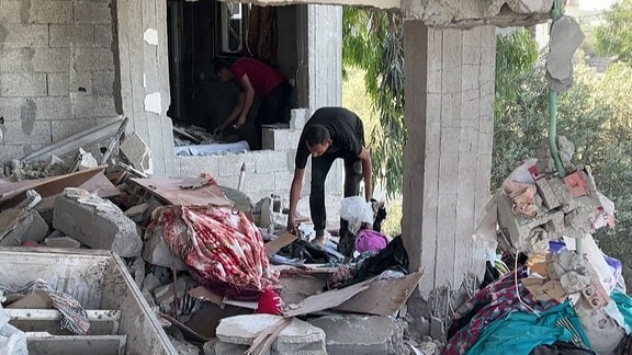 Menschen in einem zerstörten Haus in Gaza.