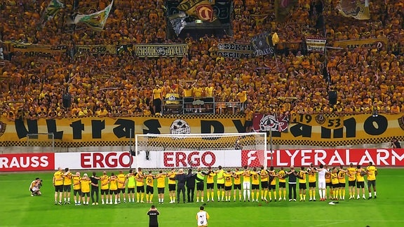 Die Mannschaft von Dynamo Dresden feiert nach einem Sieg mit den Fans auf der Tribüne.