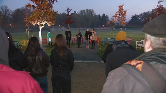 Einige Menschen haben sich zu einer Gedenkveranstaltung in einem Park versammelt.