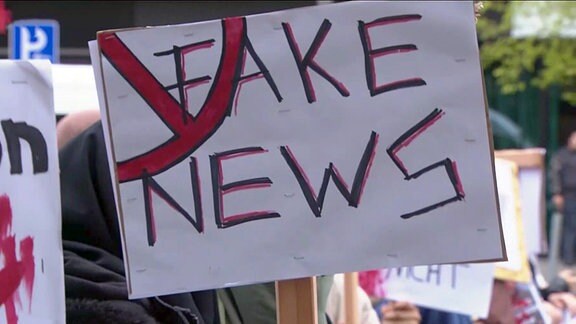 Demonstrierende halten ein Transparent: Fake News