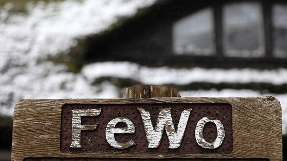 Ein Schild vor einem schneebedeckten Haus weist auf eine freie Ferienwohnung hin.