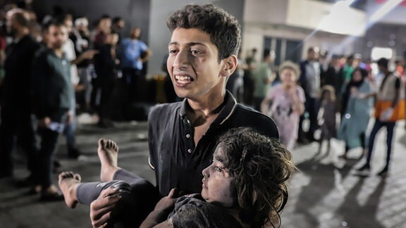 Ein junger Palästinenser trägt ein Kind aus dem Ahli Arab Krankenhaus in Richtung Al-Shifa Krankenhaus im Gazastreifen. 