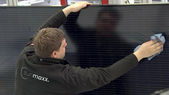 Ein Mitarbeiter putzt ein Solarpanel
