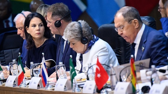 Annalena Baerbock (2.v.l., Bündnis 90/Die Grünen), Außenministerin, sitzt nur drei Plätze neben Sergej Lawrow (r), Außenminister von Russland, zu Beginn der ersten Arbeitssitzung des G20-Außenministertreffens in Rio de Janeiro zum Thema «The G20’s role in dealing with the ongoing international tensions».