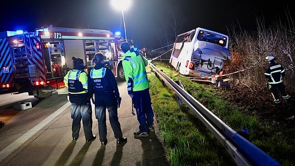 Einsatzkräfte der Feuerwehr und Polizei arbeiten an einer Unfallstelle auf der Autobahn 44 (A44) an einem verunfallten Bus.