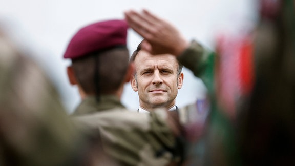 Ein Soldat salutiert vor Emmanuel Macron, Präsident von Frankreich, als dieser an einer Zeremonie zu Ehren der Saint Marcel Maquis, einer Gruppe französischer Widerstandskämpfer im Zweiten Weltkrieg, und der französischen Fallschirmjäger des SAS (Special Air Service), am Vorabend der Landung in der Normandie zum 80. Jahrestag des D-Day teilnimmt.