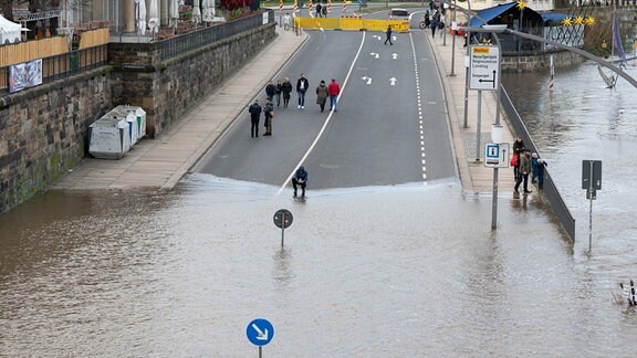 Das Hochwasser der Elbe umgibt ein Verkehrsschild am Terrassenufer in Dresden.