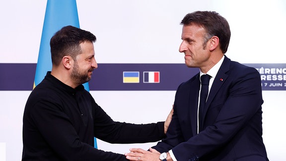 Der ukrainische Präsident Wolodymyr Selenskyj (l) schüttelt dem französischen Präsidenten Emmanuel Macron im Elysee-Palast während einer gemeinsamen Pressekonferenz die Hand.