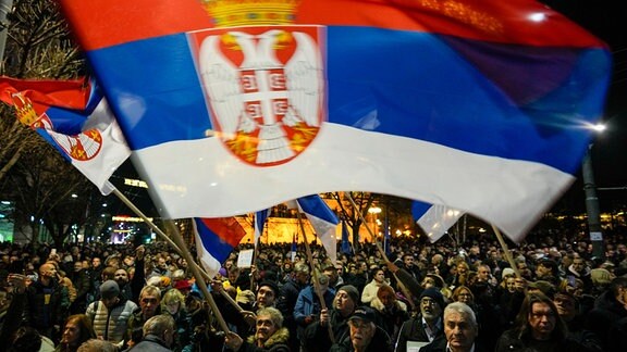 Ein Anhänger der Opposition schwenkt die serbische Nationalfahne während einer Demonstration vor dem Gebäude der Wahlkommission. 