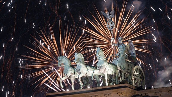 Feuerwerk zum Jahreswechsel steigt hinter dem Brandenburger Tor auf.