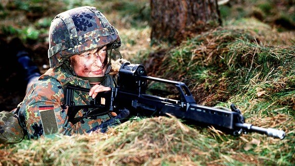 Bundeswehrsoldatin mit dem Gewehr im Anschlag während einer Geländeübung