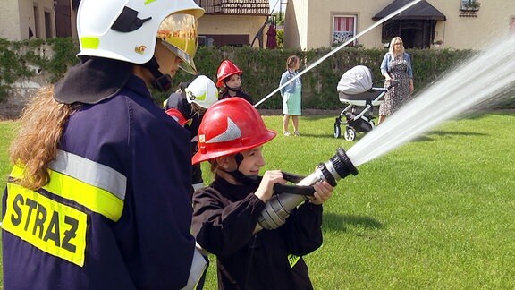 Mädchen in Feuerwehruniformen mit Löschspritzen